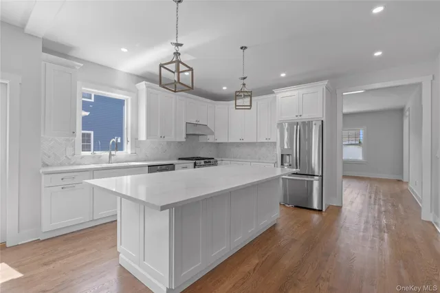 a large white kitchen with lots of counter space wooden floor appliances and windows
