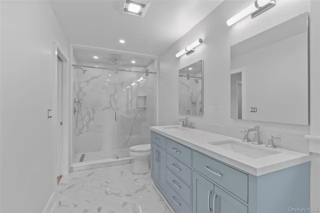 a bathroom with a sink a toilet a large mirror and shower