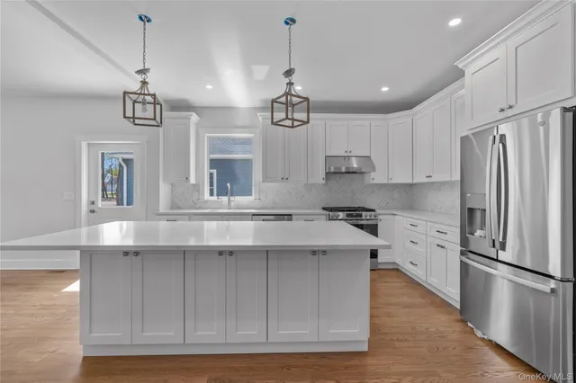 a kitchen with kitchen island white cabinets and stainless steel appliances