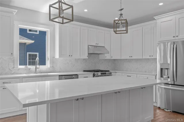 a kitchen with stainless steel appliances a sink a stove a refrigerator and cabinets