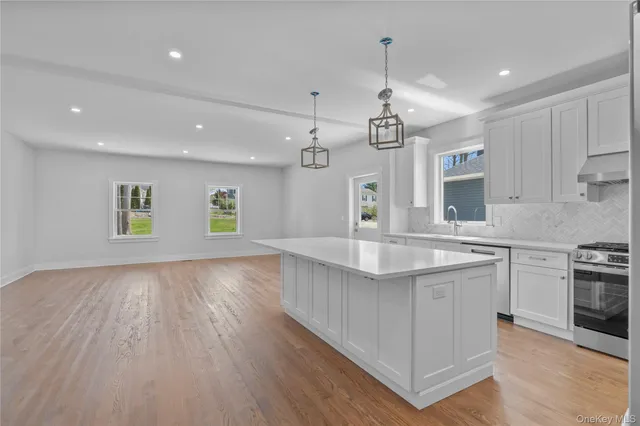 a kitchen with kitchen island granite countertop a sink cabinets and wooden floor