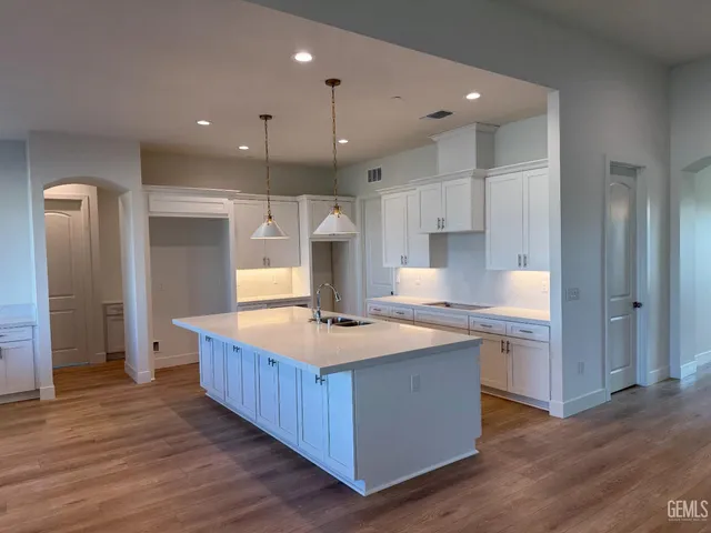 a large kitchen with kitchen island a stove a sink a refrigerator and a wooden floor