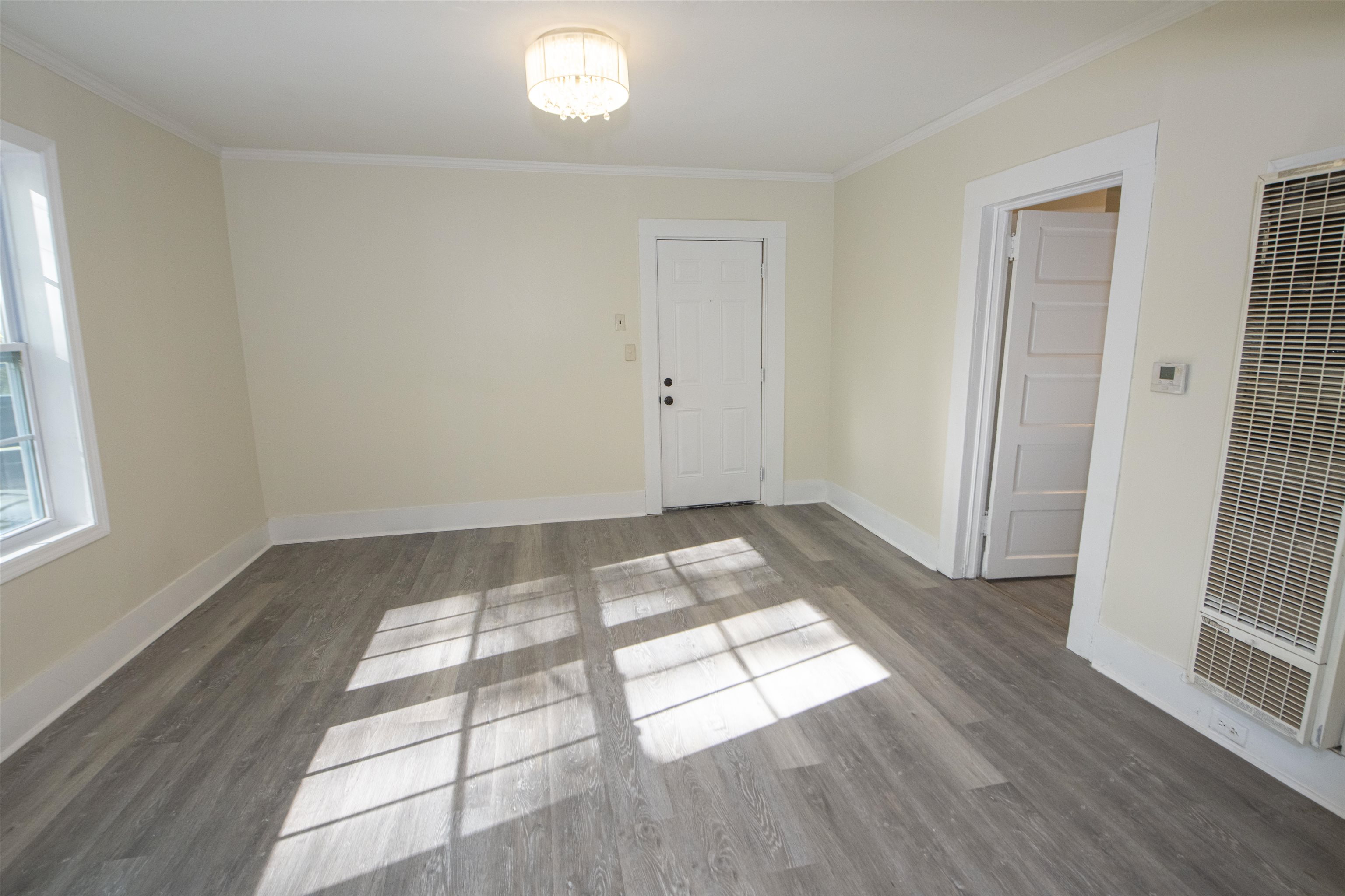 899 Craft Road Memphis, TN 38116 - Photo 10 of 13 Empty room featuring a notable chandelier, baseboards, ornamental molding, a heating unit, and wood finished floors