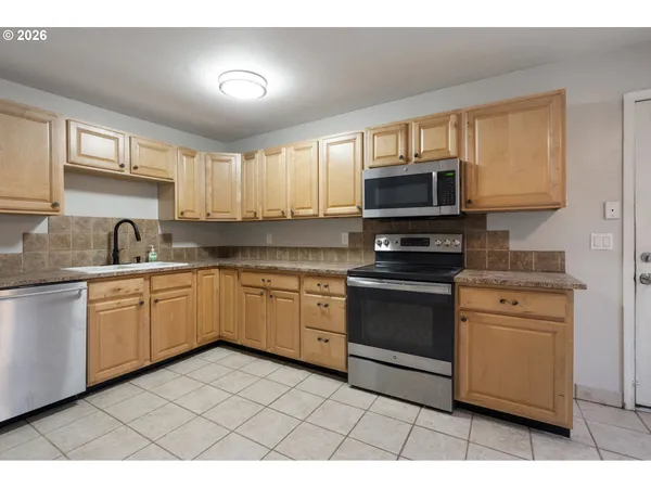 a kitchen with stainless steel appliances granite countertop a stove a sink and a microwave