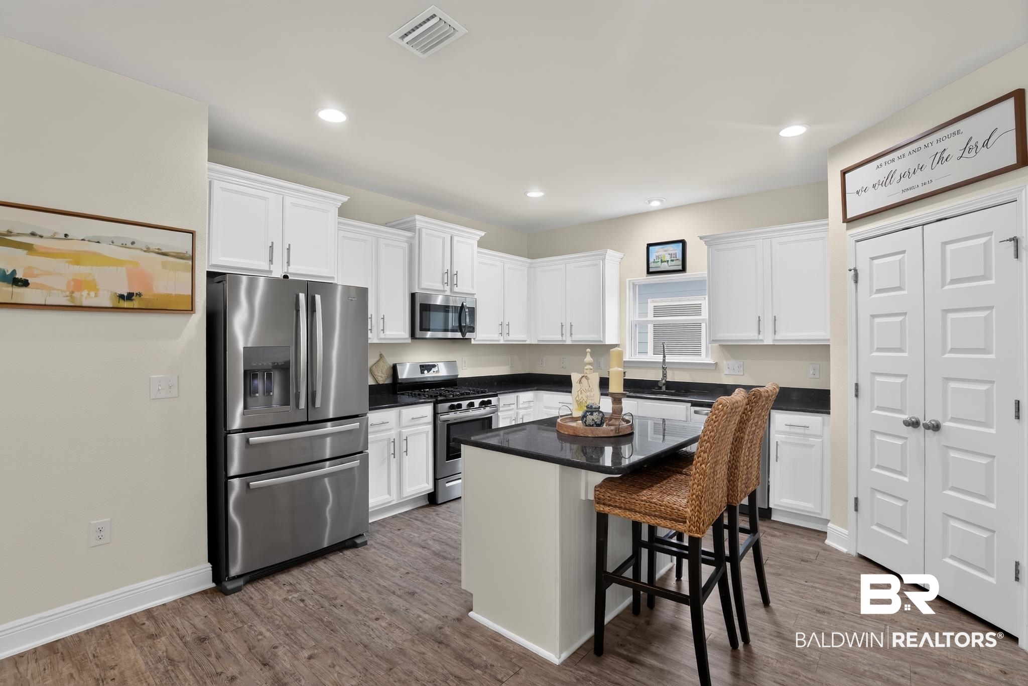 1210 Primrose Lane Foley, AL 36535 - Photo 10 of 33 Modern kitchen featuring white cabinetry with crown molding, stainless steel appliances, dark countertops, and wood-finish flooring