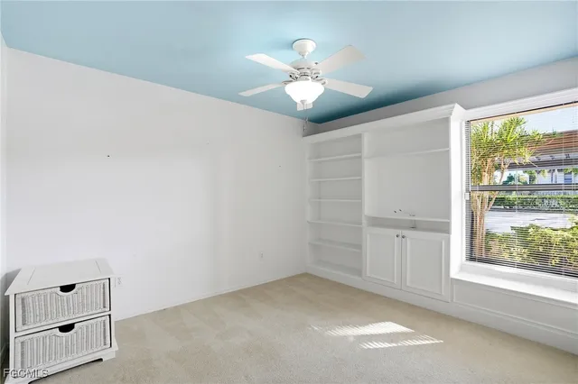an empty room with windows and chandelier fan