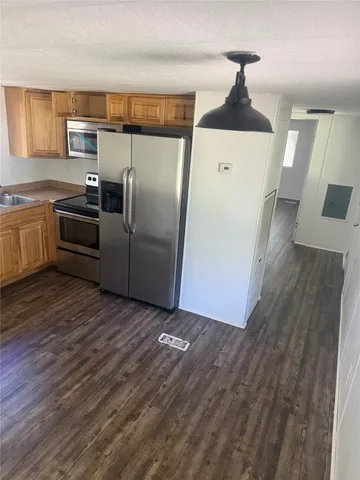 a kitchen with granite countertop a refrigerator and a stove top oven