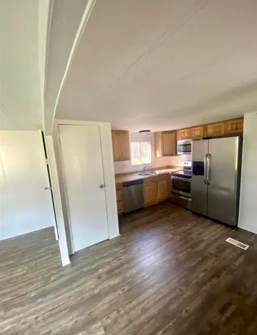 a view of a kitchen with refrigerator and wooden floor