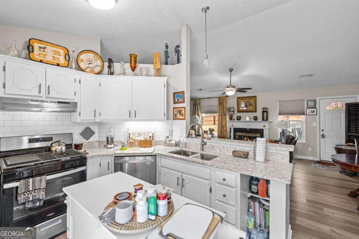 6324 Amberly Road Rex, GA 30273 - Photo 14 of 22 a kitchen with a sink dishwasher a stove a dining table and chairs with wooden floor