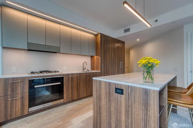 a kitchen with stainless steel appliances a stove a chimney a sink and cabinets