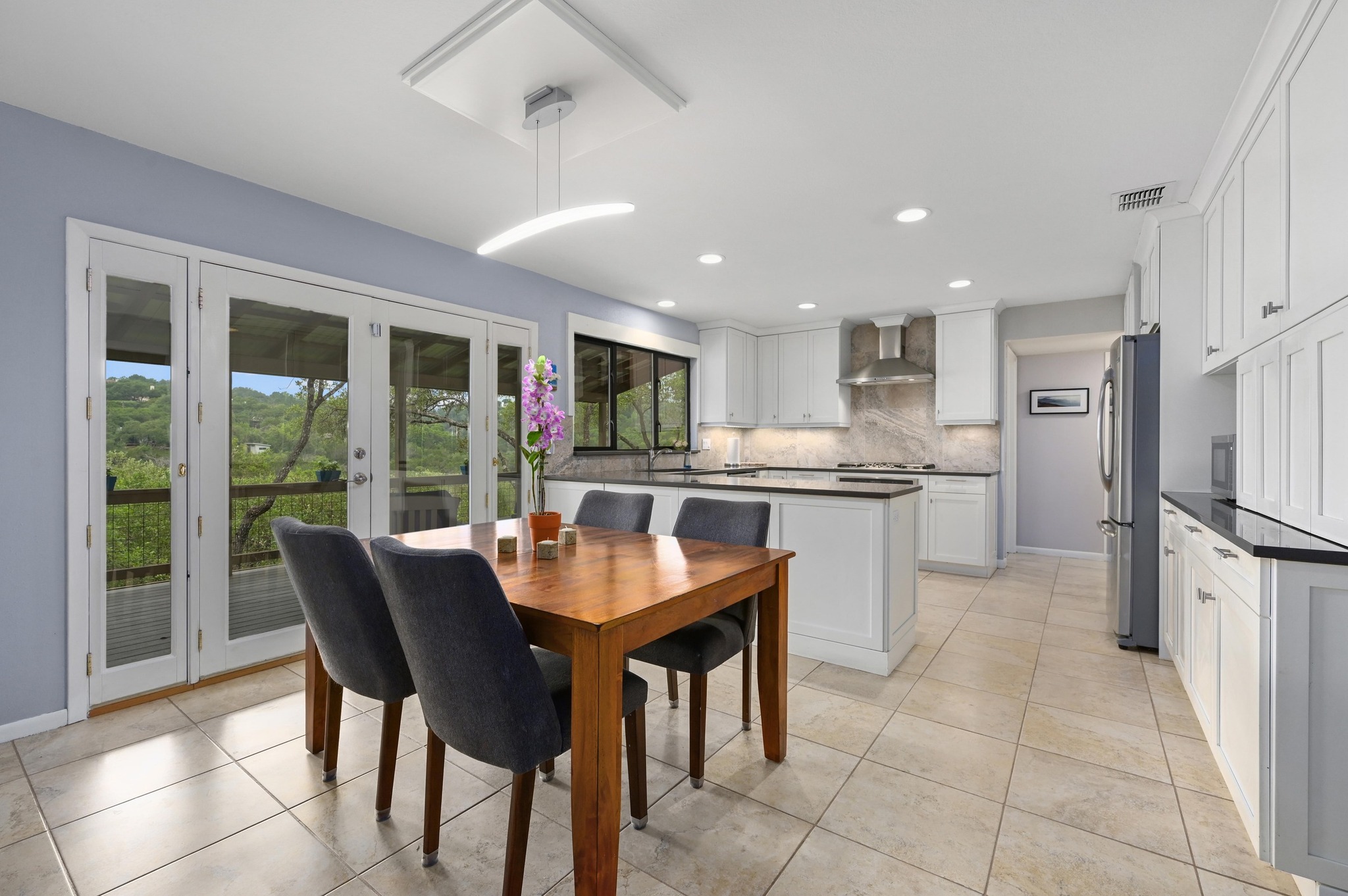 2009 South Oak Canyon Road Austin, TX 78746 - Photo 12 of 37 a kitchen with stainless steel appliances granite countertop a stove a refrigerator a sink dishwasher a dining table and chairs with wooden floor