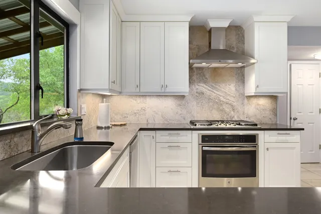 a kitchen with granite countertop a sink stainless steel appliances and cabinets
