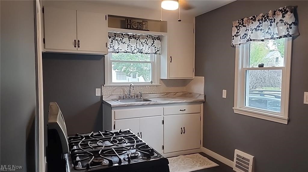 23621 Colbourne Road Euclid, OH 44123 - Photo 29 of 45 Kitchen with black gas range, sink, white cabinets, and plenty of natural light