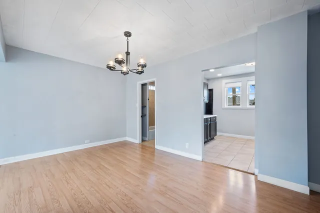 a view of a hallway with wooden floor and a chandelier