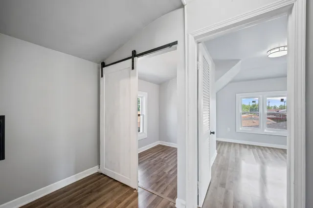 a view of an empty room with wooden floor and a window