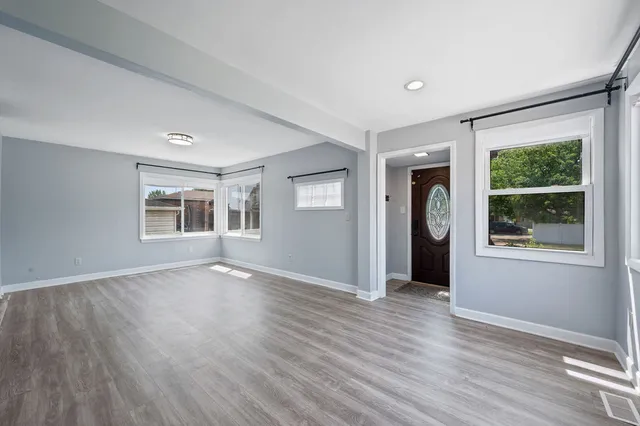 a view of an empty room with a window and wooden floor