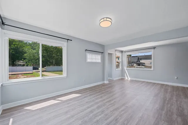 a view of an empty room with a window and wooden floor