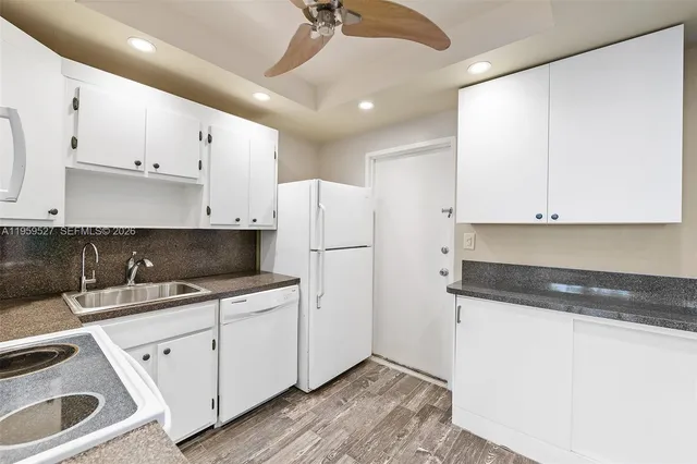 a kitchen with a sink a refrigerator and white cabinets