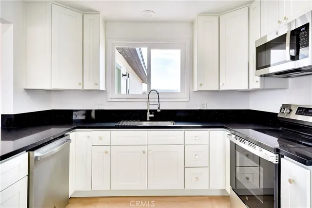 a kitchen with stainless steel appliances granite countertop a sink a stove and cabinets