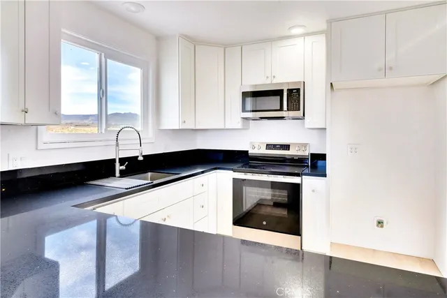 a kitchen with granite countertop a sink stainless steel appliances and white cabinets