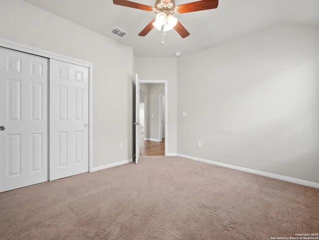 a view of an empty room and chandelier fan