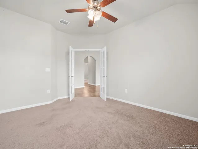 an empty room with chandelier fan and closet area