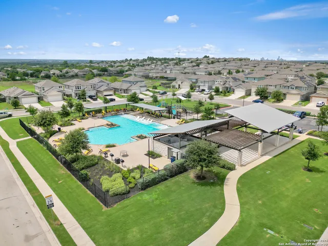 an aerial view of residential houses with outdoor space and trees