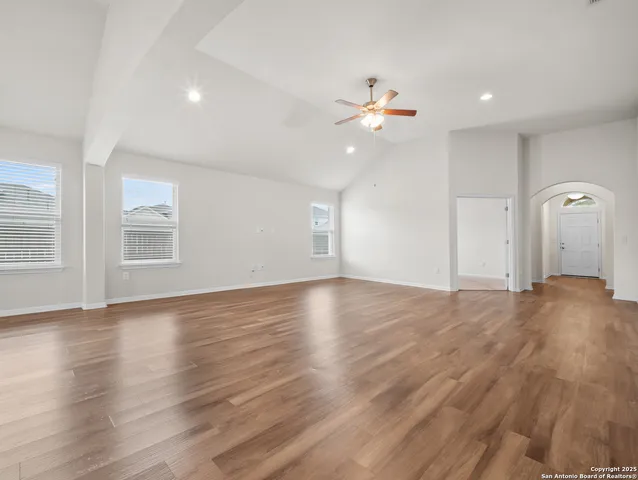 a view of an empty room with window and wooden floor
