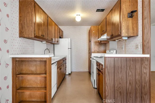 a kitchen with stainless steel appliances granite countertop a refrigerator a stove and a sink with wooden cabinets
