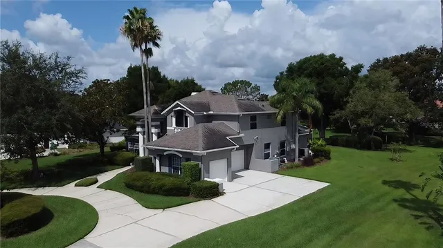a view of a house with a big yard potted plants and a large tree