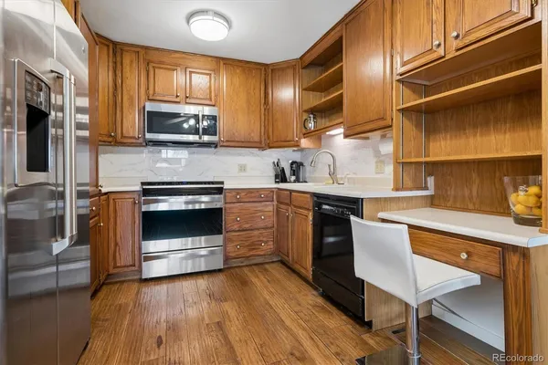 a kitchen with stainless steel appliances a stove a sink dishwasher a microwave oven with cabinets and wooden floor