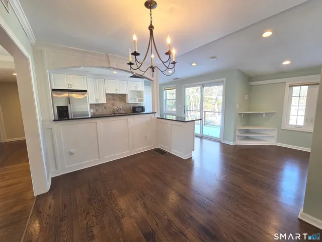 a view of a kitchen with granite countertop wooden floor stainless steel appliances and a chandelier