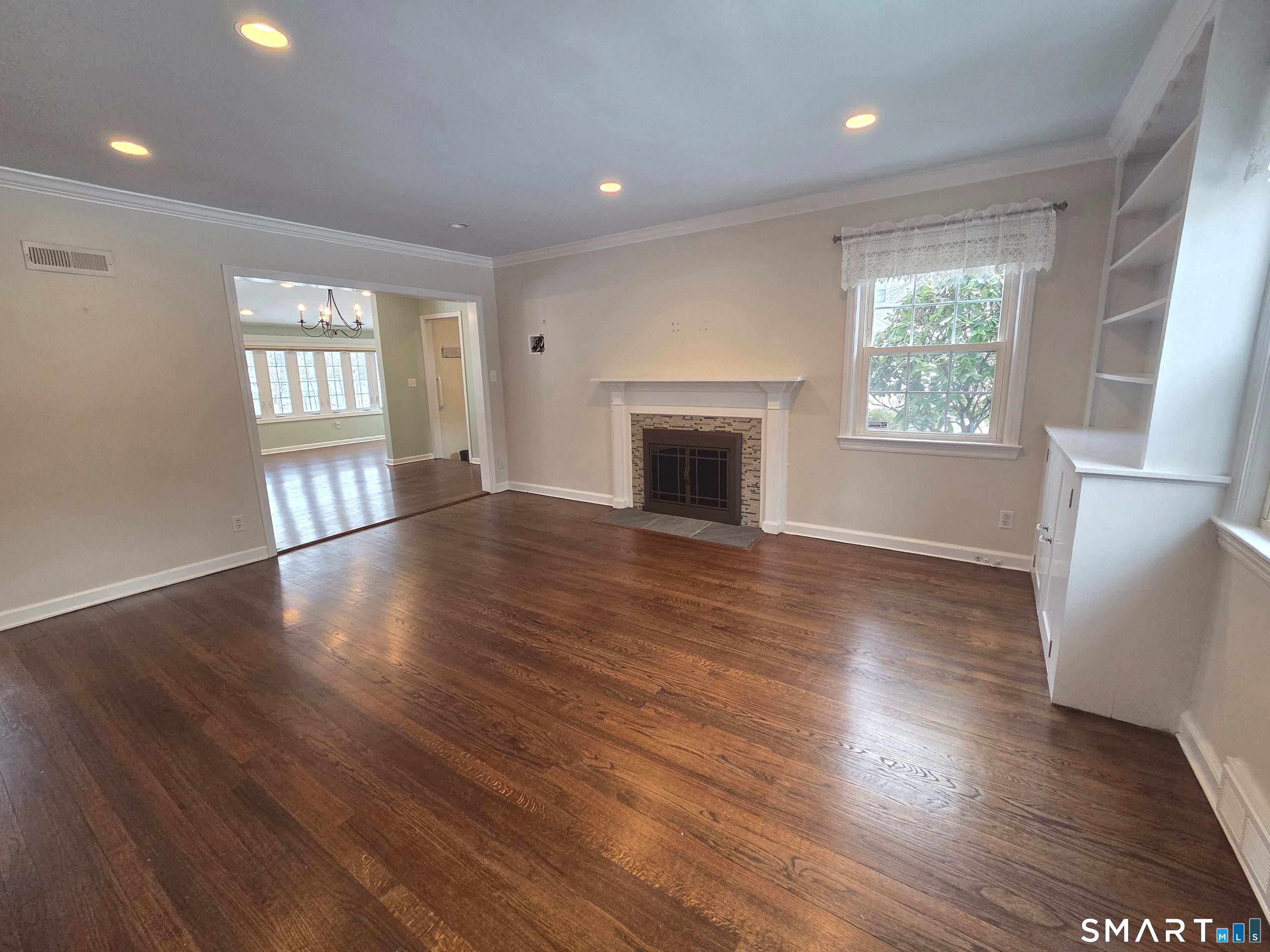 51 Glendale Road Stamford, CT 06905 - Photo 6 of 17 an empty room with wooden floor fireplace and windows