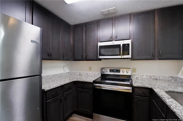 a kitchen with granite countertop stainless steel appliances sink and cabinets