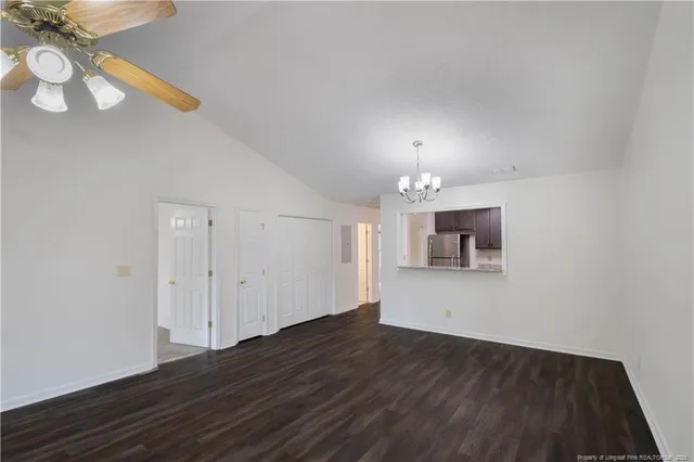 a view of an empty room with wooden floor and a chandelier
