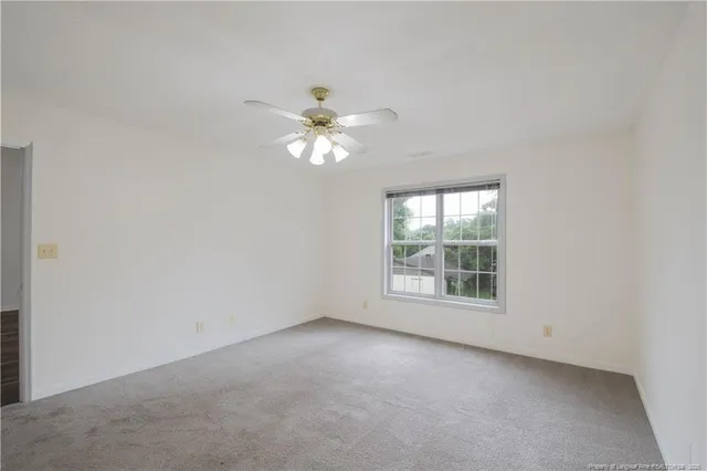 a view of an empty room with a chandelier fan