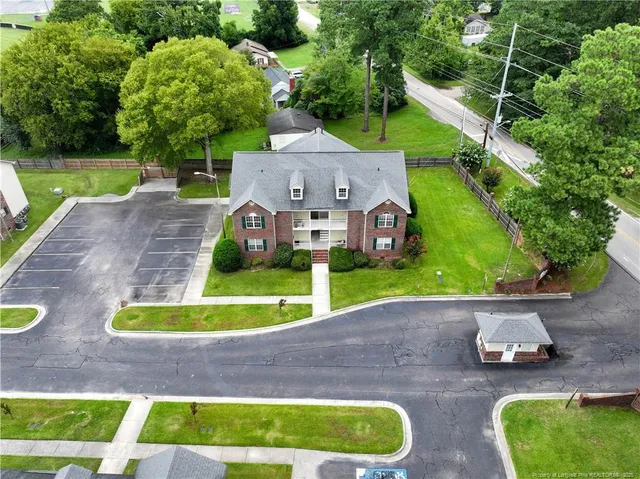 a view of a house with a big yard plants and large trees