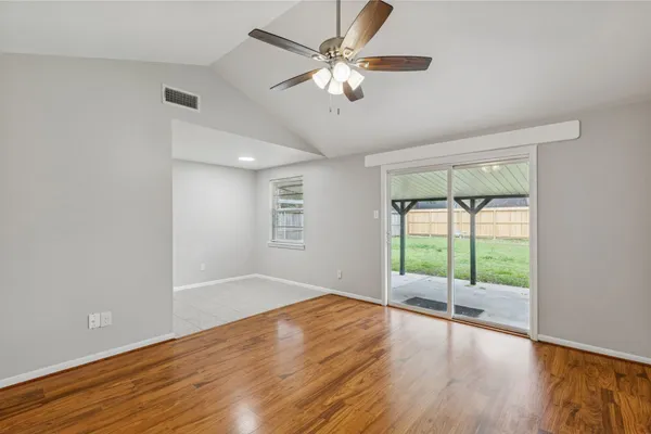 a view of an empty room with wooden floor and a window