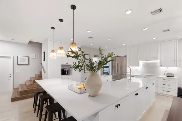 a kitchen with stainless steel appliances a dining table chairs and a refrigerator