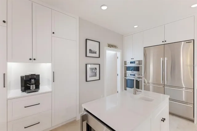 a large kitchen with stainless steel appliances kitchen island granite countertop a sink a large window and a view of living room