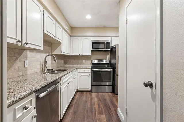 a kitchen with granite countertop a sink stove and refrigerator