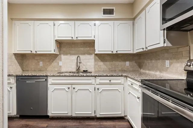 a kitchen with granite countertop white cabinets and a sink