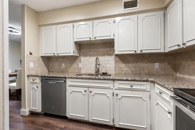 a kitchen with stainless steel appliances granite countertop a stove a sink and white cabinets
