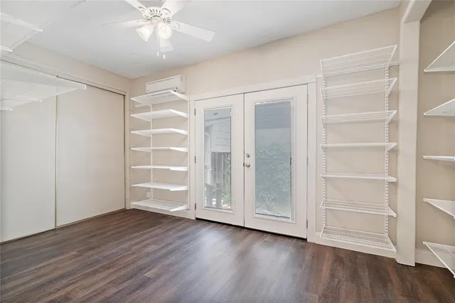 an empty room with wooden floor closet and windows