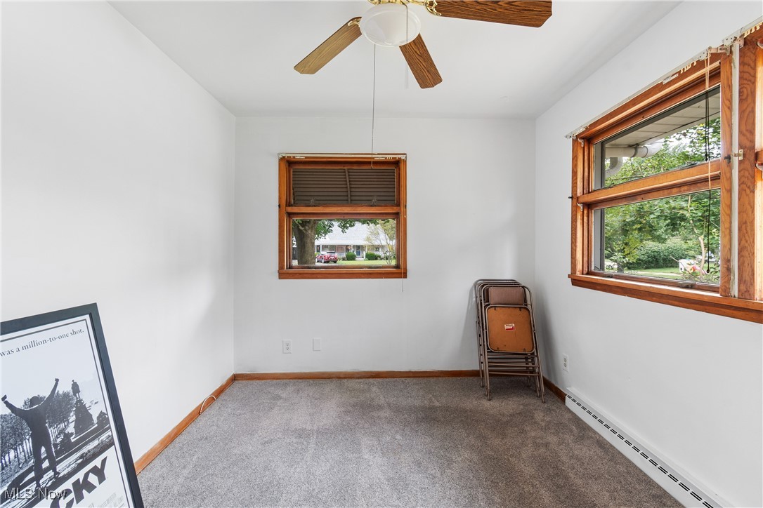 1067 Munroe Falls Kent Road Kent, OH 44240 - Photo 18 of 31 Spare room featuring a baseboard radiator, carpet, and ceiling fan