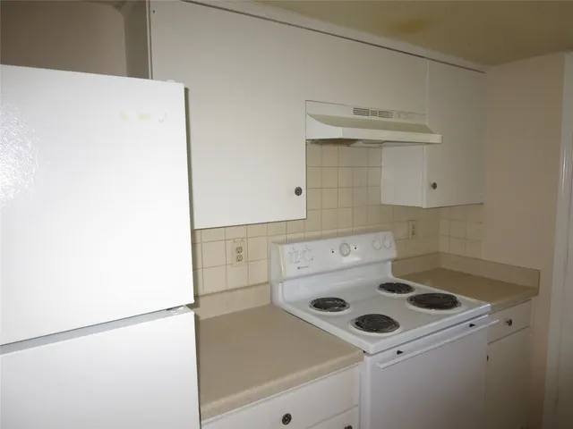 a white refrigerator freezer a stove and white cabinets