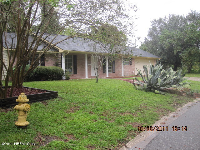 5103 Damascus Road West Jacksonville, FL 32207 - Photo 3 of 23 a view of a white house with a yard and table and chairs under an umbrella