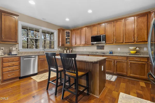 a kitchen with stainless steel appliances granite countertop a kitchen island a stove a table and chairs