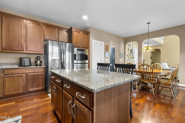 a kitchen with granite countertop a stove a sink a dining table and chairs