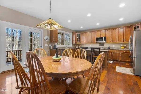 a kitchen with kitchen island a dining table chairs and white cabinets